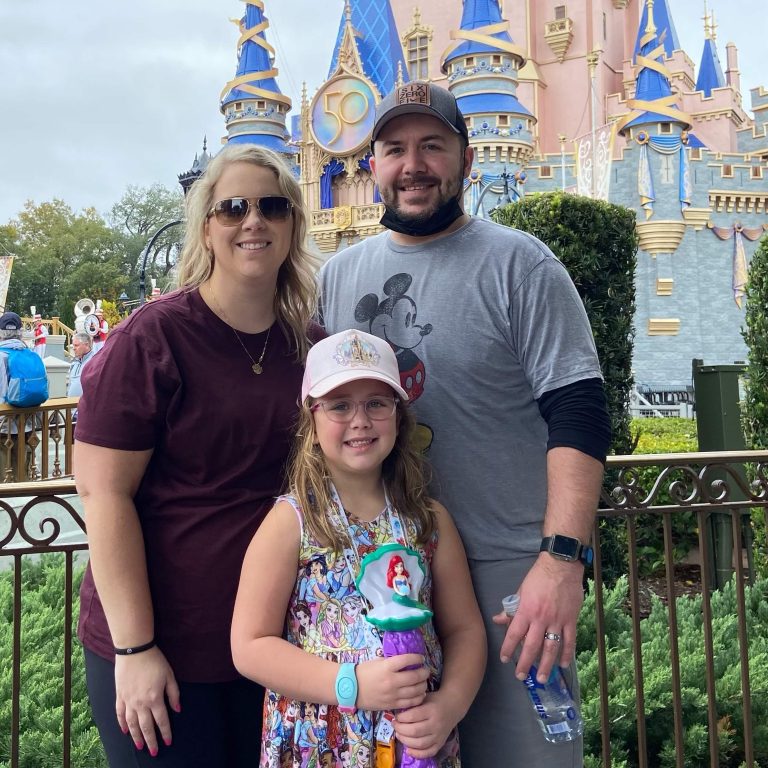 a family portrait of Kristan Morris with her husband and daughter at DisneyWorld